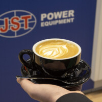 Cafe at Ennovation Austria Latte with JST Power Equipment branding in the background at Ennovation 2025