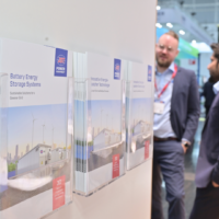 Informational brochures from JST Power Equipment highlighting battery storage, sustainable solutions, and energy innovation at a trade show. Brochures on energy storage and sustainability displayed in clear holders at a trade show booth.