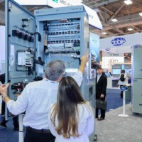 Attendees viewing an open electrical panel at JST Power Equipment’s DISTRIBUTECH 2025 booth