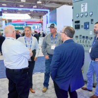 Attendees around JST Power Equipment booth with Medium Voltage Switchgear in background at DISTRIBUTECH 2025