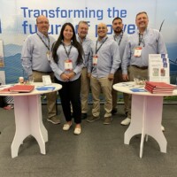 The JST Power Equipment team at RE+ Mexico 2025, presenting their commitment to transforming the future of power. Five JST Power Equipment team members standing in front of their booth at RE+ Mexico 2025, with a branded backdrop and promotional materials on display tables.