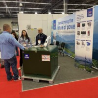JST team at RE+ Mexico showcasing transformer and switchgear solutions for a cleaner energy future. JST booth at RE+ Mexico with a green transformer and attendees around its promotional materials on display.