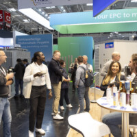 Industry professionals connect and exchange ideas at The Smarter E Europe 2025, highlighting the importance of networking in the renewable energy sector. Attendees gather and socialize at an exhibition booth during The Smarter E Europe 2025, engaging in conversation and refreshments.